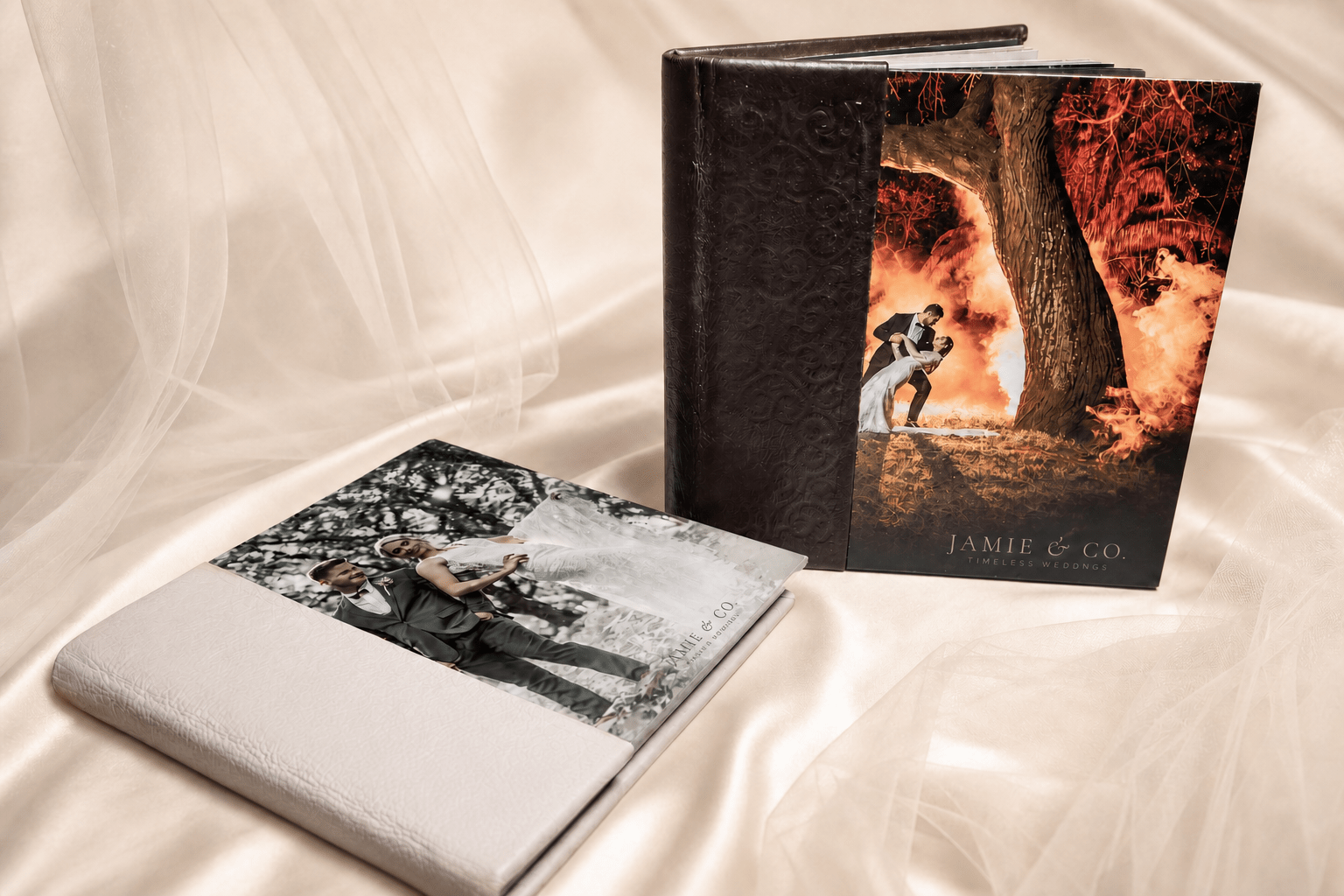 Jamie and Co luxury leather-bound wedding albums displayed on ivory satin