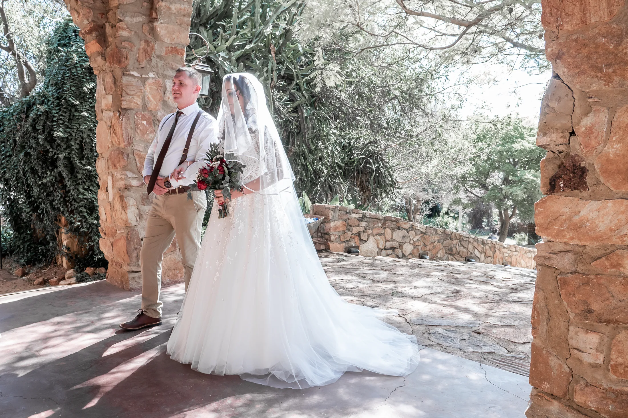 Armand and Melanie standing beneath a stone arch