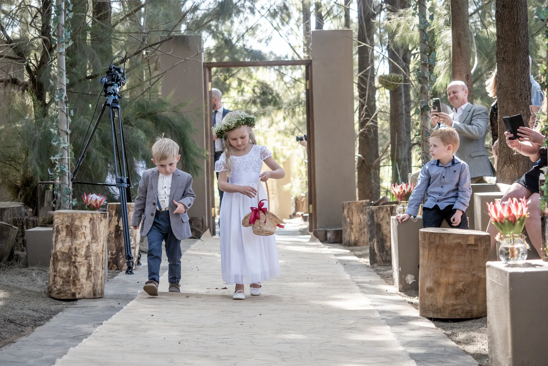 Young flower girls walking into the forest ceremony