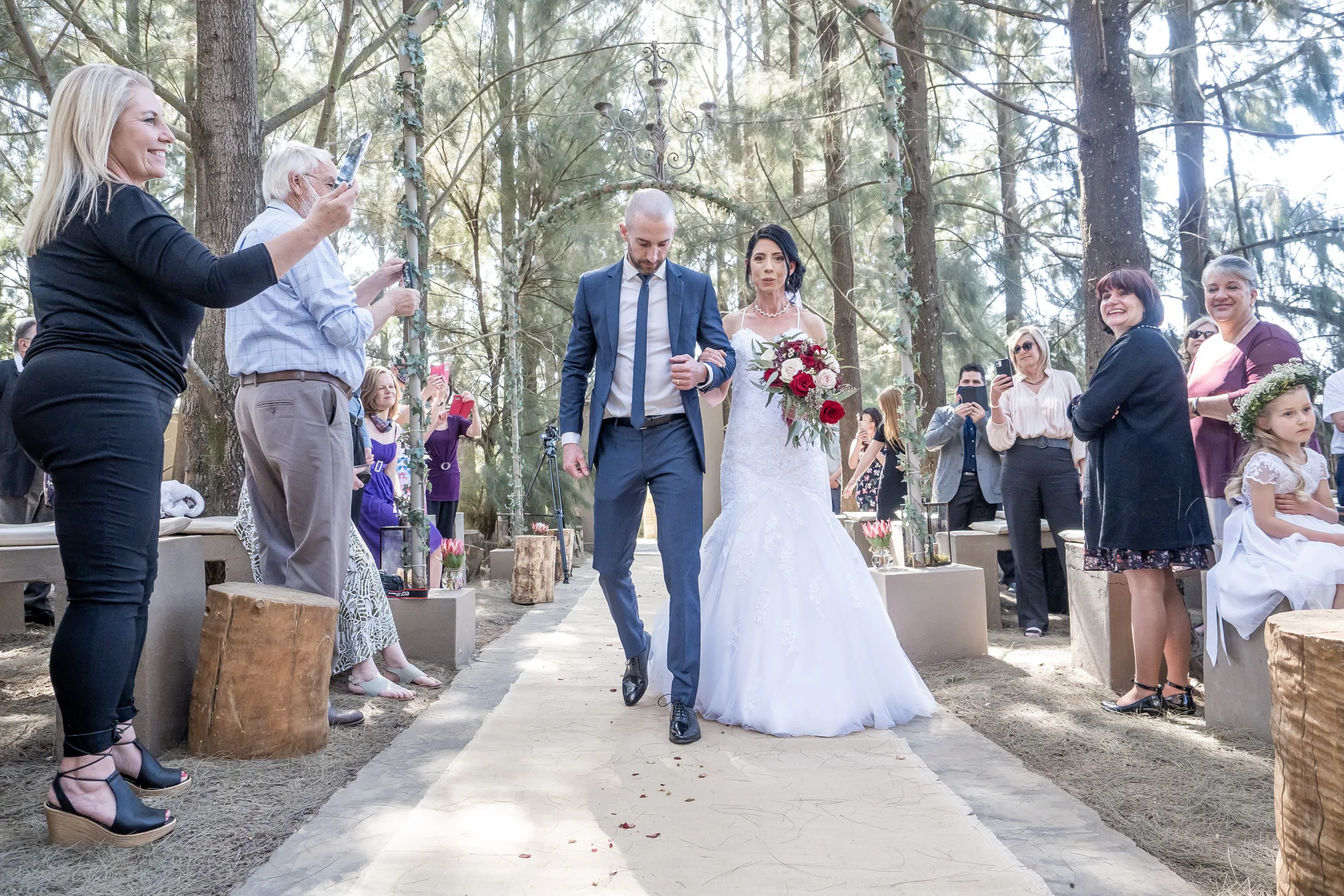 Karen walking down the aisle beneath the pine trees