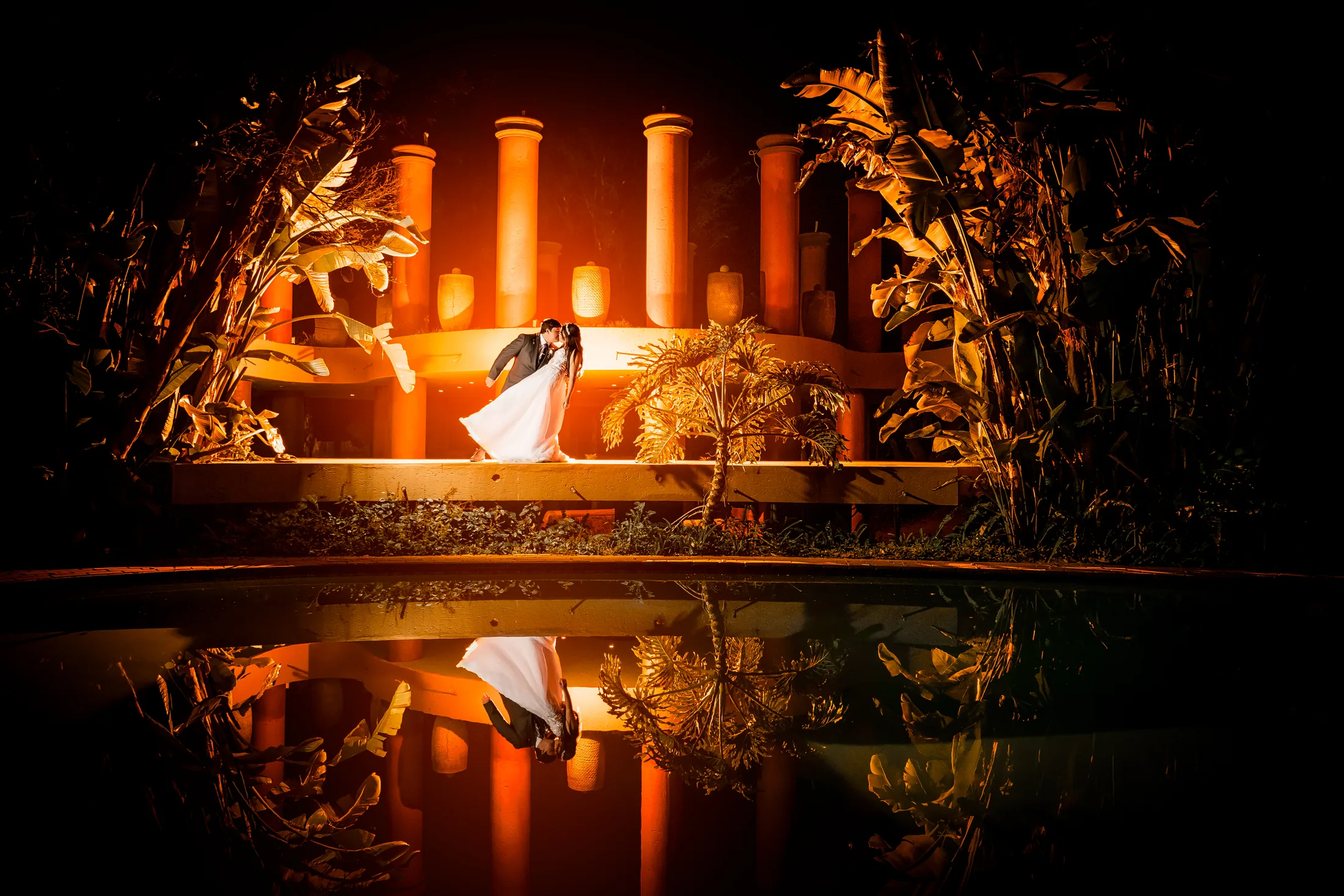 Franco and Anastasia kissing beside the illuminated pool at Galagos Country Estate at night